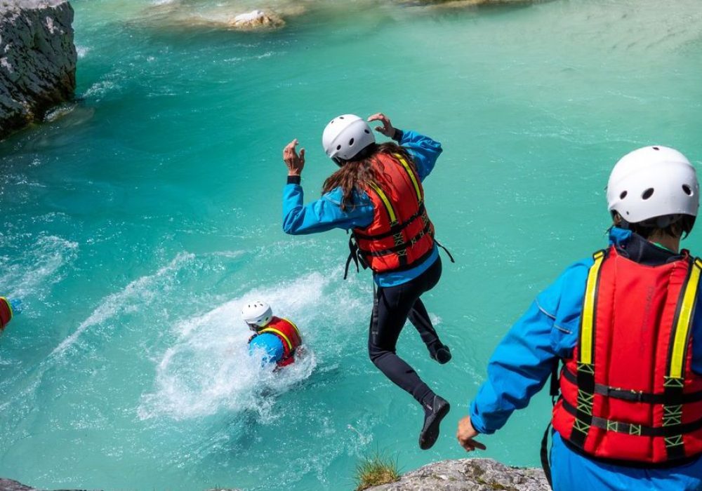 Adventurous teambuilding in mountains. Adrenaline jumping into cold water in gorge. Amazing turquoise clear water in Soca river, Slovenia.